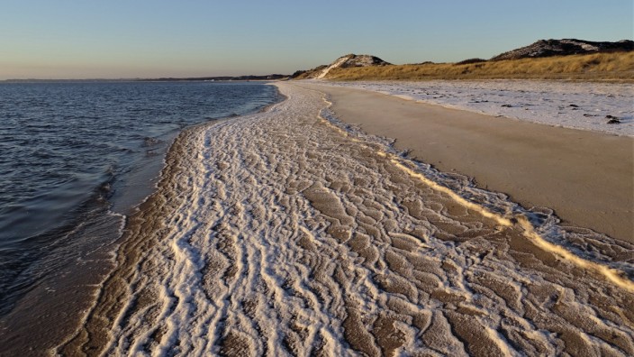 Nature-Writing-Buchreihe: Wenn der Nordseestrand gefroren ist, hinterlassen die Wellen bei Ebbe Bänder aus Eiskristallen.