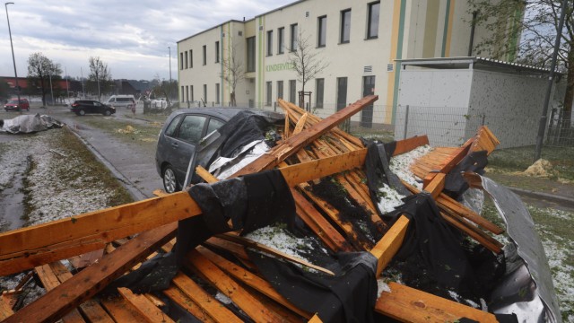 Unwetter in Bayern: Ein vom Sturm abgetragenes Dach eines Seniorenheims liegt auf einem Parkplatz auf einem Auto.