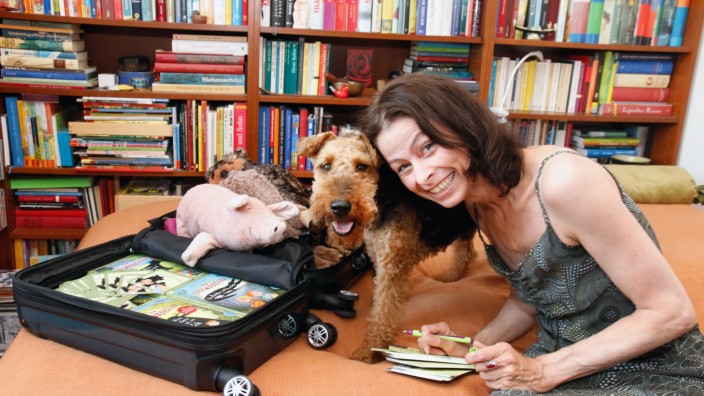 Kinderbücher aus dem Fünfseenland: Martina Baumbach mit ihrem Hund Pelle, ein paar Kuscheltieren und einem Vorlesekoffer mit Kinderbüchern.