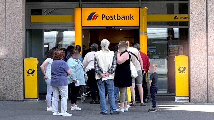 SZ am Morgen: Kunden stehen in einer Warteschlange vor einer Filiale einer Postbank in Düsseldorf.