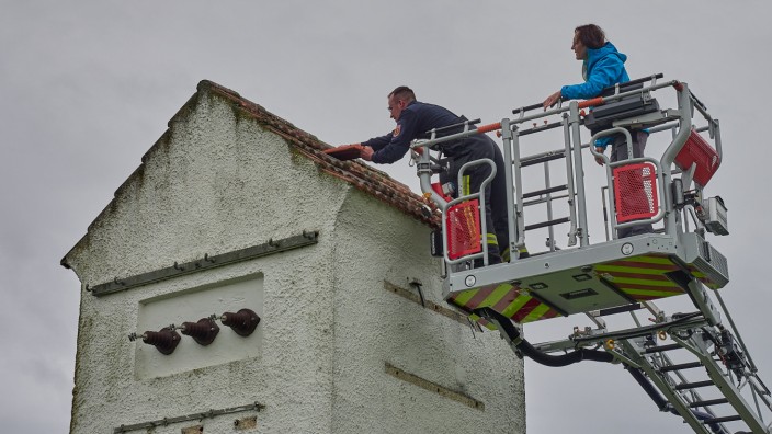 Artenvielfalt erhalten: Christoph Mainusch von der Feuerwehr und Roswitha Holzmann von der Unteren Naturschutzbehörde setzen am Dach eine spezielle "Einflugsplatte" ein.