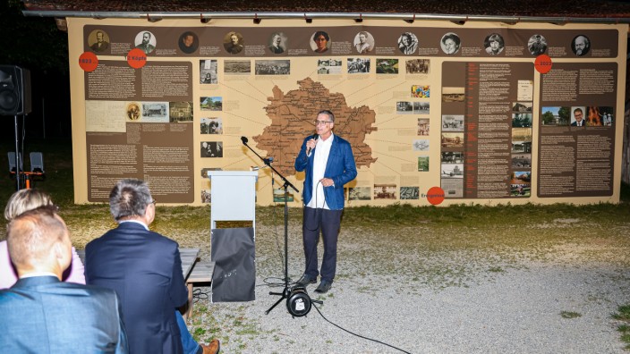 Schöngeising: Museumsleiter Reinhard Jakob eröffnet die Sonderausstellung vor der an einer Außenwand angebrachten Grafik.