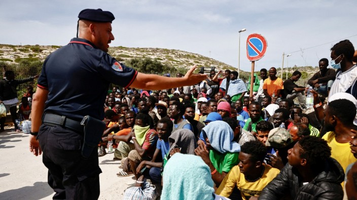 Asyl: Das Mittelmeer überlebt: ankommende Flüchtlinge auf Lampedusa, dirigiert von einem italienischen Polizisten.