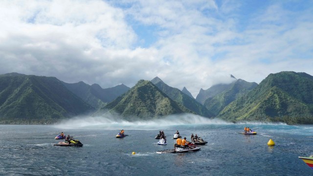 Surfen: Surreale Schönheit: Vor den grünen Hängen Tahitis warten Jetskis darauf, die Surfer in die hohen Wellen zu fahren. Nahe der Küste soll für Olympia nun ein neuer Turm entstehen.