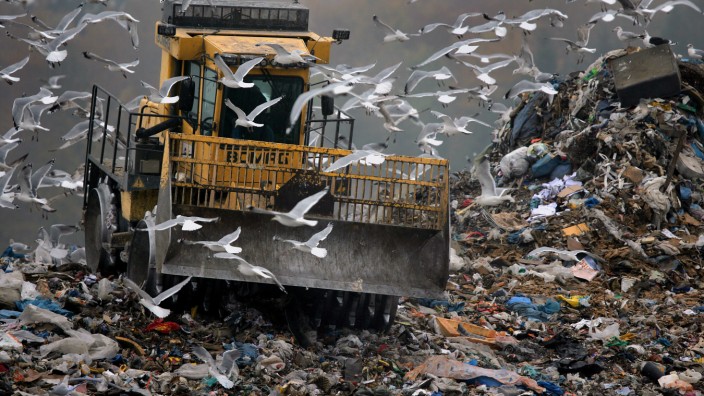 Verpackungsverordnung: Zwischengelagerter Hausmüll wird von einem Verdichter auf einer Deponie verschoben. Ein neues Gesetz soll die riesigen Müllberge verringern.