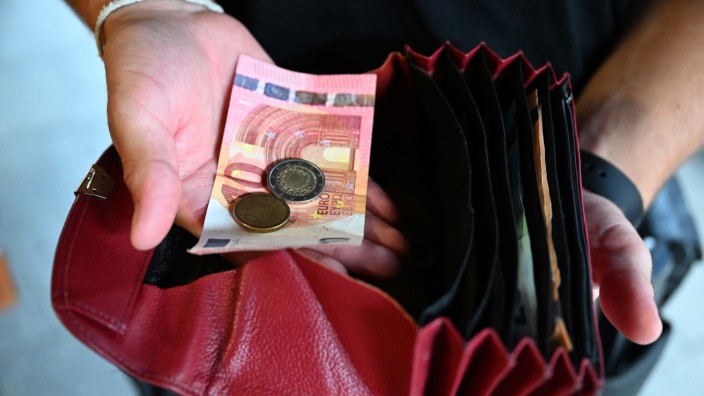 Geld und Inflation: Ein Kellner eines Restaurants hält einen Geldbeutel in der Hand: Die Löhne legen zu.