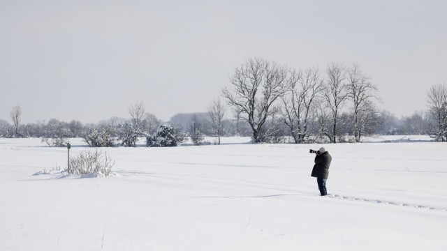 Winterchaos: Ein Flugzeugspotter im Schnee beobachtet die Enteisungsarbeiten am Flughafen München.