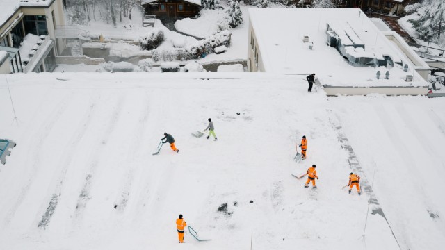 Wintereinbruch: Einsatzkräfte von Feuerwehr und Bauhof schippen in Ottobrunn den Schnee vom Dach des Phönix-Hallenbads. Wegen der Schneelast ist das Bad sicherheitshalber derzeit geschlossen.