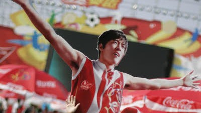 Facholympisch (26): Ein kleiner Junge posiert vor einem Bild des chinesischen Leichtathleten Liu Xiang, dessen überraschendes Ausscheiden wenig erfreulich für seine Sponsoren war.