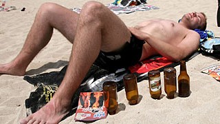 Ein paar Flaschen Bier, Sonne und abends Party: ein Deutscher Tourist schlummert im Sand des "Ballermanns" auf Mallorca