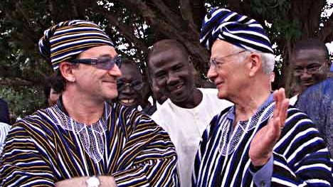 Rockstar scherzt mit Politiker in Ghana im Jahre 2002: Bono mit Paul O'Neill, dem damaligen US-Finanzminister, in traditionellem Wams