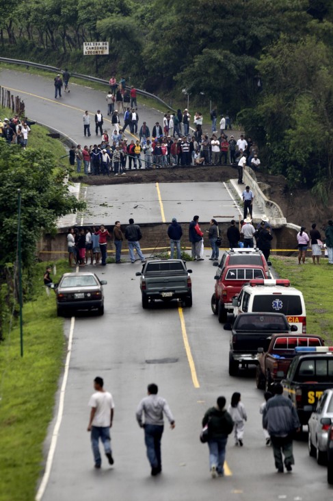 People on a highway watch as a bridge is washed away by rain water after Hurricane Agatha, in Barberena