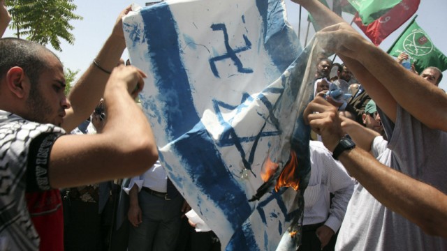 Jordanian protestors burn a banner with an image of a defaced Israeli flag during a demonstration outside the Jordanian prime ministry in Amman