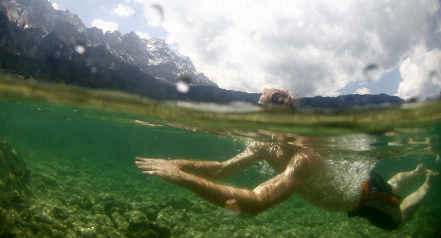 A man swims in the Eibsee lake in front of Germany's highest mountain Zugspitze during a sunny summer day in Grainau