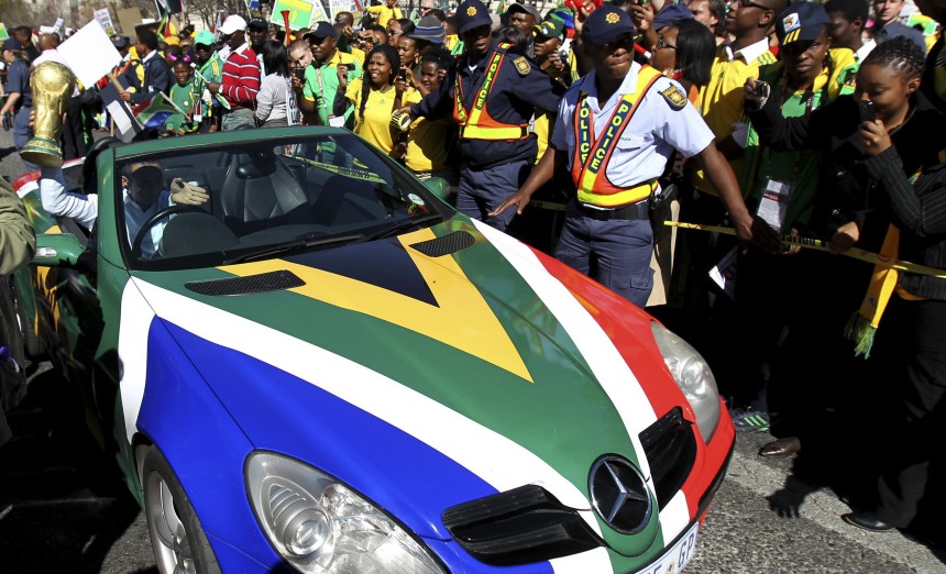 Fan carries mock World Cup trophy while driving car painted in South African colours during parade for South Africa's national soccer team in Johannesburg