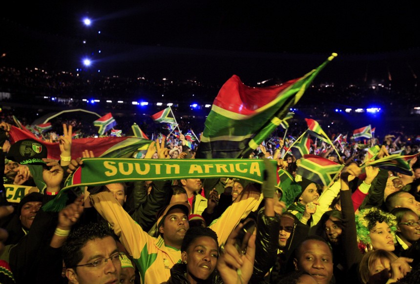 Fans raise scarves and wave flags during the opening concert for the 2010 World Cup at the Orlando Stadium in Soweto