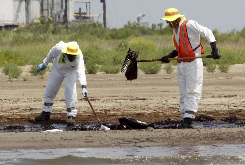 Workers try to remove oil from the Deepwater Horizon wellhead off the beach in Grand Terre Isle in Barataria Bay, Louisiana