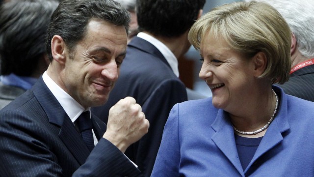 France's President Nicolas Sarkozy gestures beside German Chancellor Angela Merkel at the start of a European Union leaders summit in Brussels