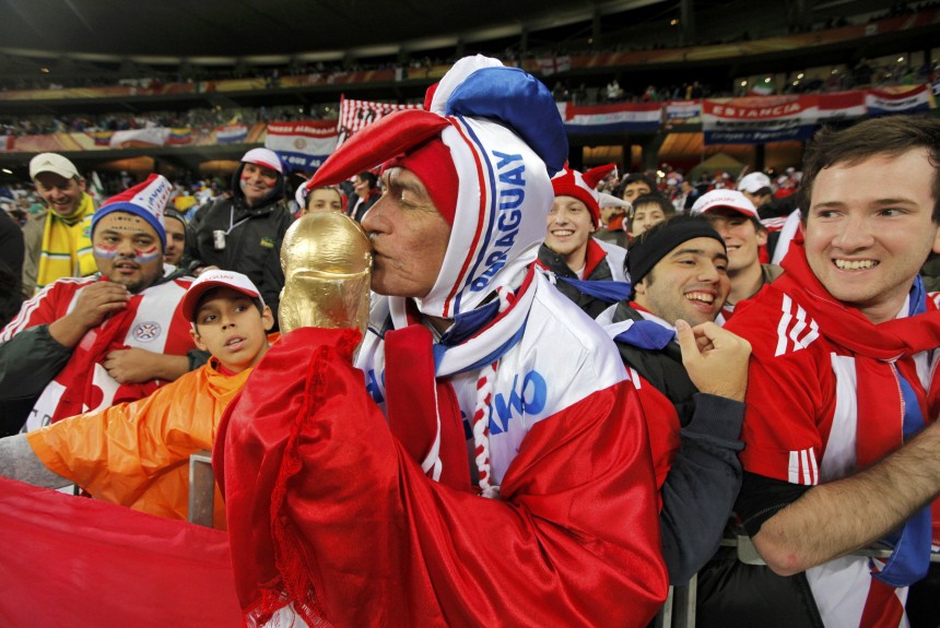 A Paraguay fan kisses a mock World Cup trophy before the start of the 2010 World Cup Group F soccer match between Paraguay and Italy at Green Point stadium in Cape Town