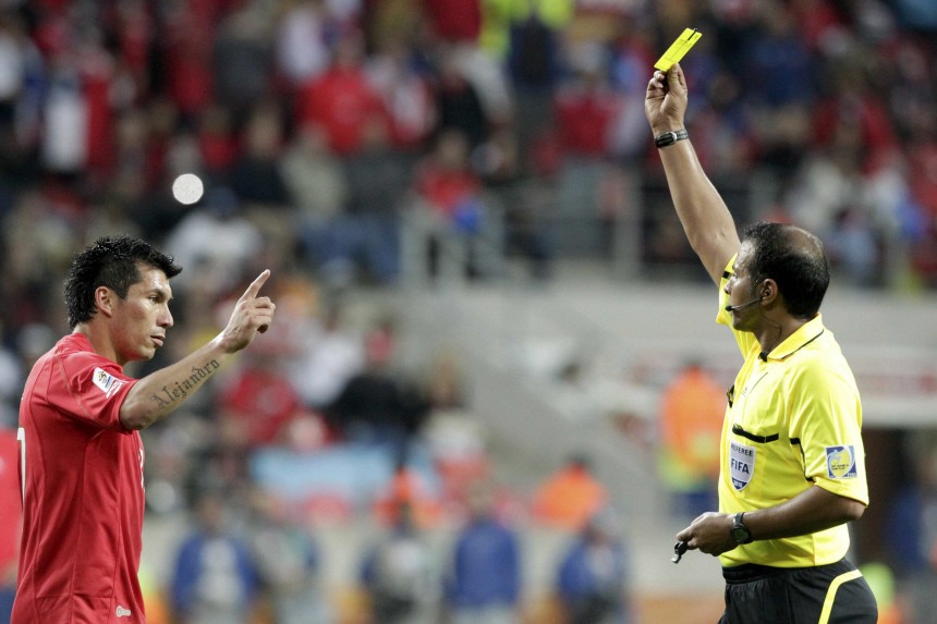 Referee Al Ghamdi of Saudi Arabia shows the yellow card to Chile's Medel during a World Cup match against Switzerland at Nelson Mandela Bay stadium in Port Elizabeth
