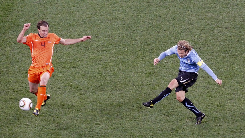 Uruguay's Forlan shoots past Netherlands' Mathijsen to score during their 2010 World Cup semi-final soccer match at Green Point stadium in Cape Town