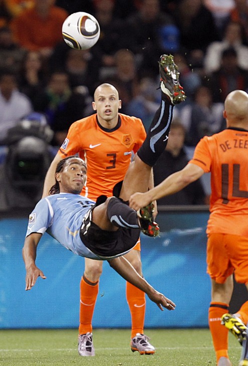 Uruguay's Alvaro Pereira kicks the ball in front of Netherlands' John Heitinga during their 2010 World Cup semi-final soccer match at Green Point stadium