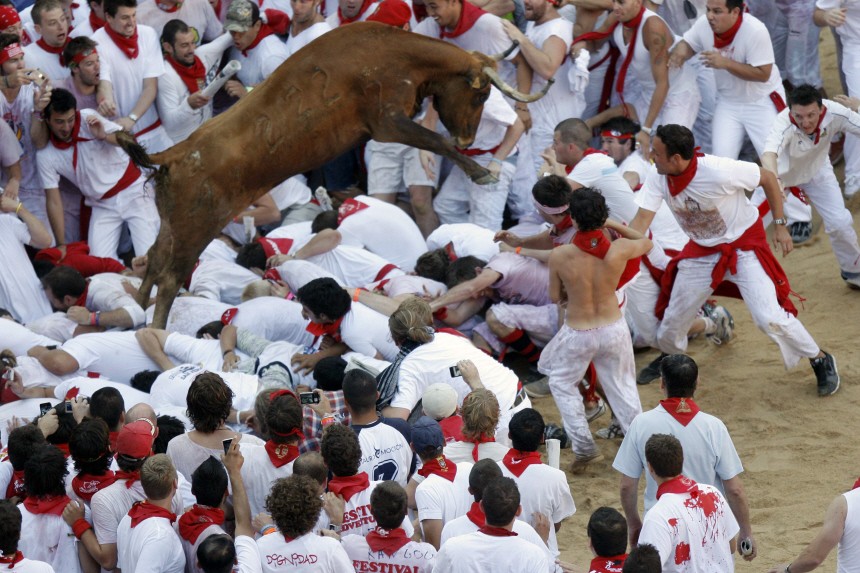 A fighting cow leaps over revellers during festivities in the bull ring during the San Fermin festival in Pamplona
