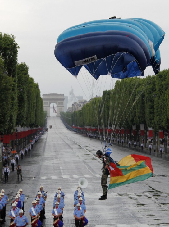 A French paratrooper with African flags prepares to land on the Champs Elysees in Paris at the end of the traditional Bastille Day parade in Paris