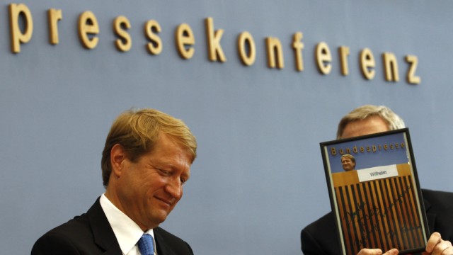 Outgoing government spokesman Wilhelm reacts as the head of the German federal press conference Goessling hands over a photograph as gift on his last news conference in Berlin