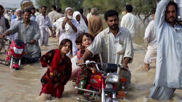 A man evacuates his children through waist-deep waters after heavy flooding in Nowshera, located in Pakistan's northwest Khyber-Pakhtunkhwa Province