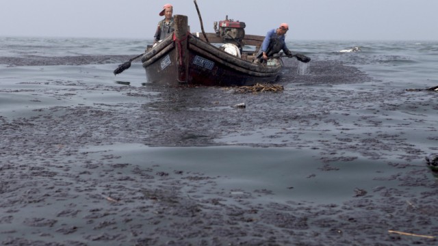 Fishermen clean up oil from the oil spill site in Dalian