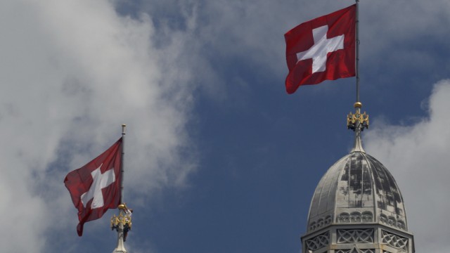 A worker adjusts a Swiss national flag atop of one of the towers of the Grossmuenster church in Zurich