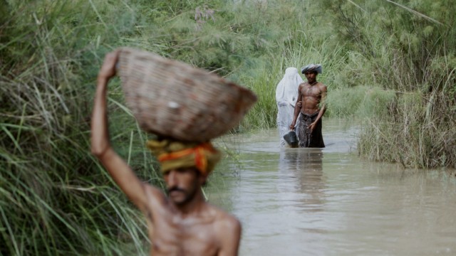 A family wades through flood waters in Shah Bela village in Sukkur at Pakistan's Sindh province