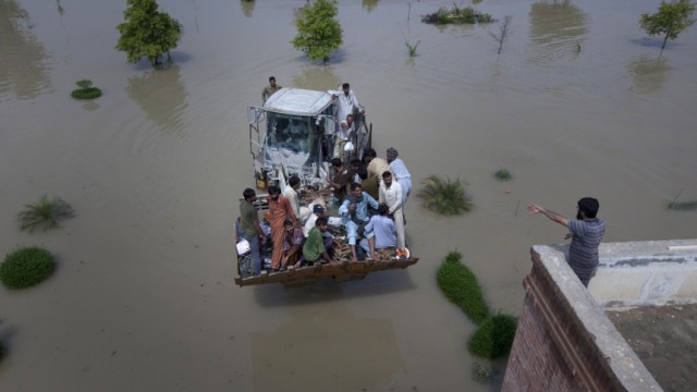 A bulldozer carries flood victims to a near by rooftop in Muzaffargarh district of Pakistan's Punjab province