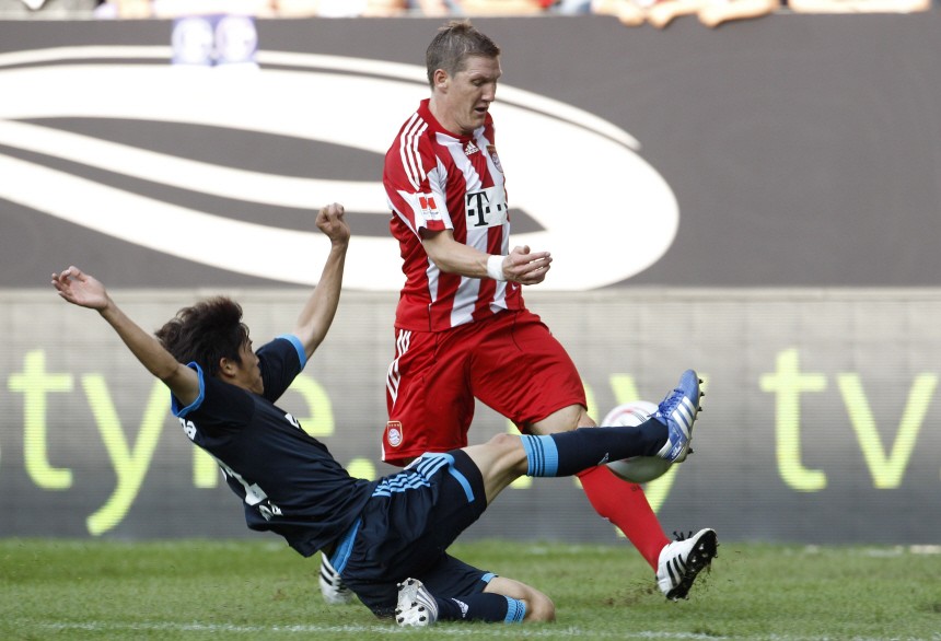 Bayern Munich's Schweinsteiger is tackled by Uchida of Schalke during Supercup final soccer match in Augsburg