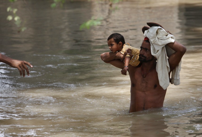 A man hands over his daughter to a naval rescue boat as he wades through floodwaters in Sukkur
