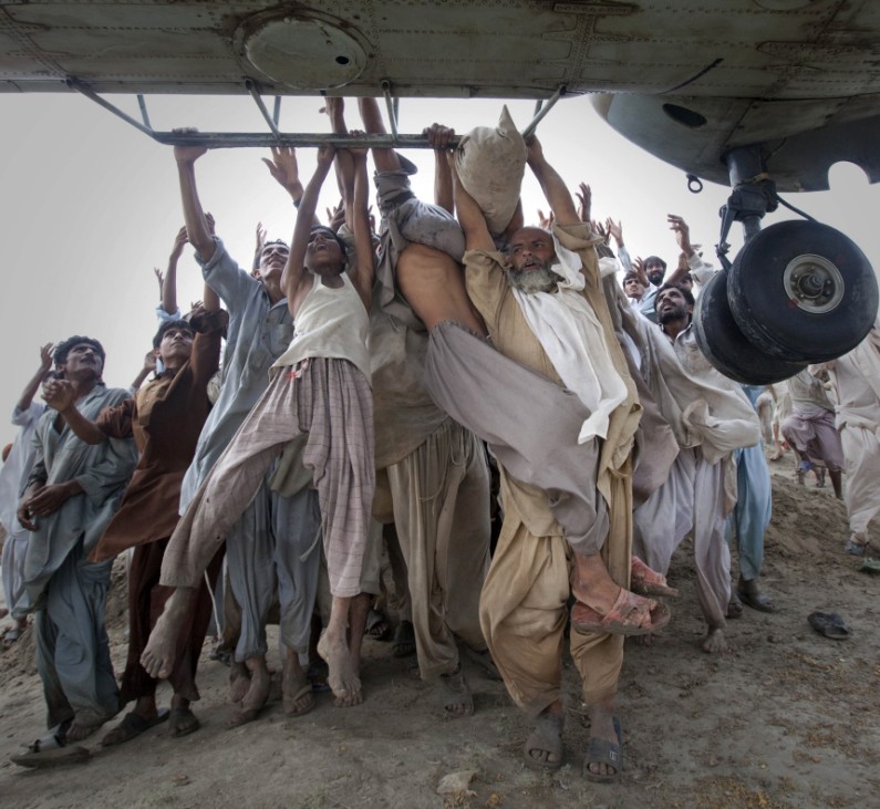 Marooned flood victims looking to escape grab the side bars of a hovering Army helicopter which arrived to distribute food supplies in the Muzaffargarh district of Pakistan's Punjab province
