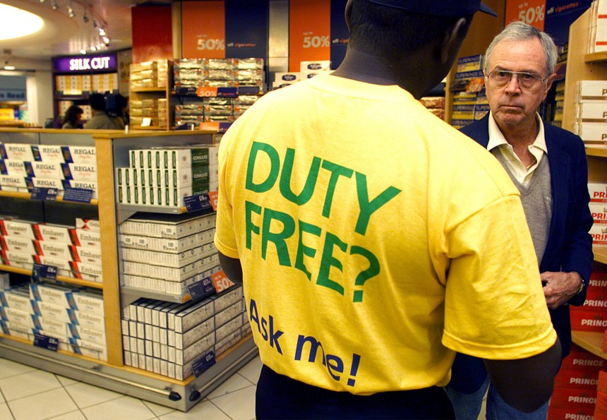 A DUTY FREE MERCHANDISER GIVES A CUSTOMER ADVICE AT GATWICK