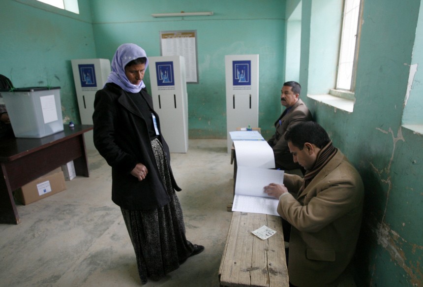 A woman waits as election workers look at her name on the voters list at a polling centre in Sinjar