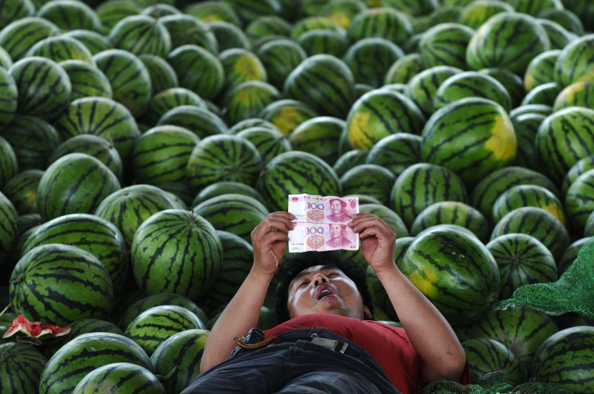 A watermelon vendor looks at yuan banknotes at a market in Changzhi