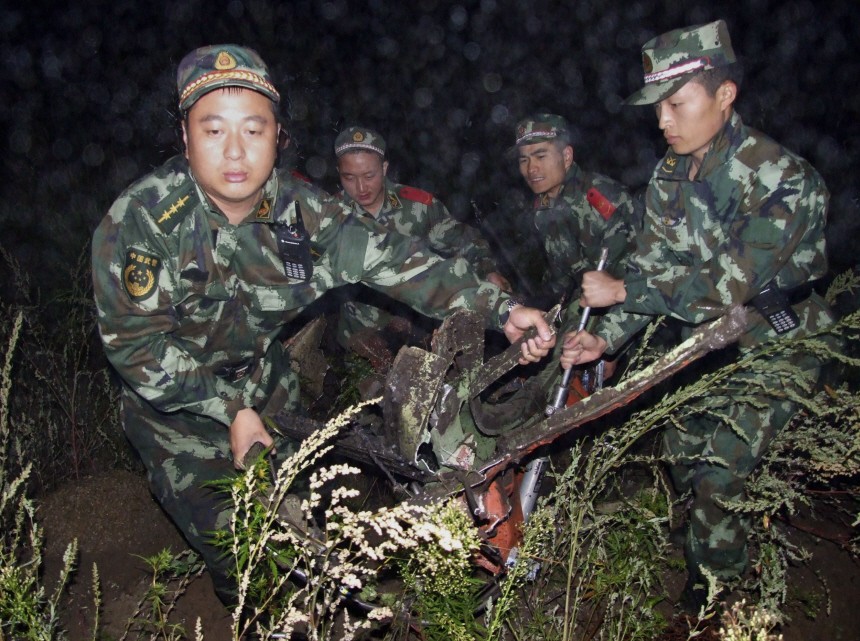 Paramilitary policemen carry the wreckage of a crashed passenger plane in Yichun