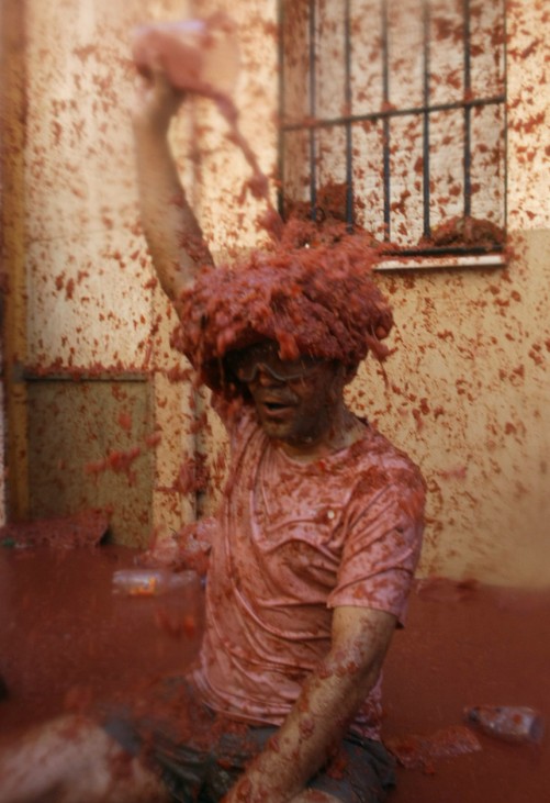 A reveller pours tomato pulp over himself after the annual 'Tomatina' (tomato fight) in the Mediterranean village of Bunol