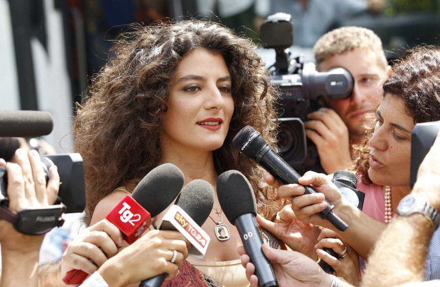 A woman speaks with the media as she arrives with other young women for a meeting with Libyan leader Gaddafi in Rome
