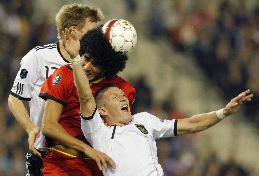 Belgium's Fellaini fights for the ball with Germany's Schweinsteiger and Mertesacker during their Euro 2012 qualifying soccer match at the King Baudouin stadium