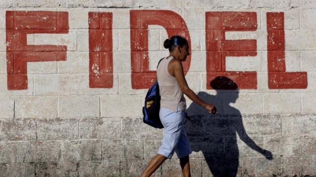 A woman walks past graffiti on a wall that reads 'Fidel', which refers to former Cuban leader Fidel Castro, in Havana