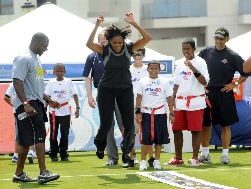U.S. first lady Obama jumps during a football drill as children and NFL officials observe, as she promotes her 'Let's Move' campaign to fight childhood obesity in New Orleans