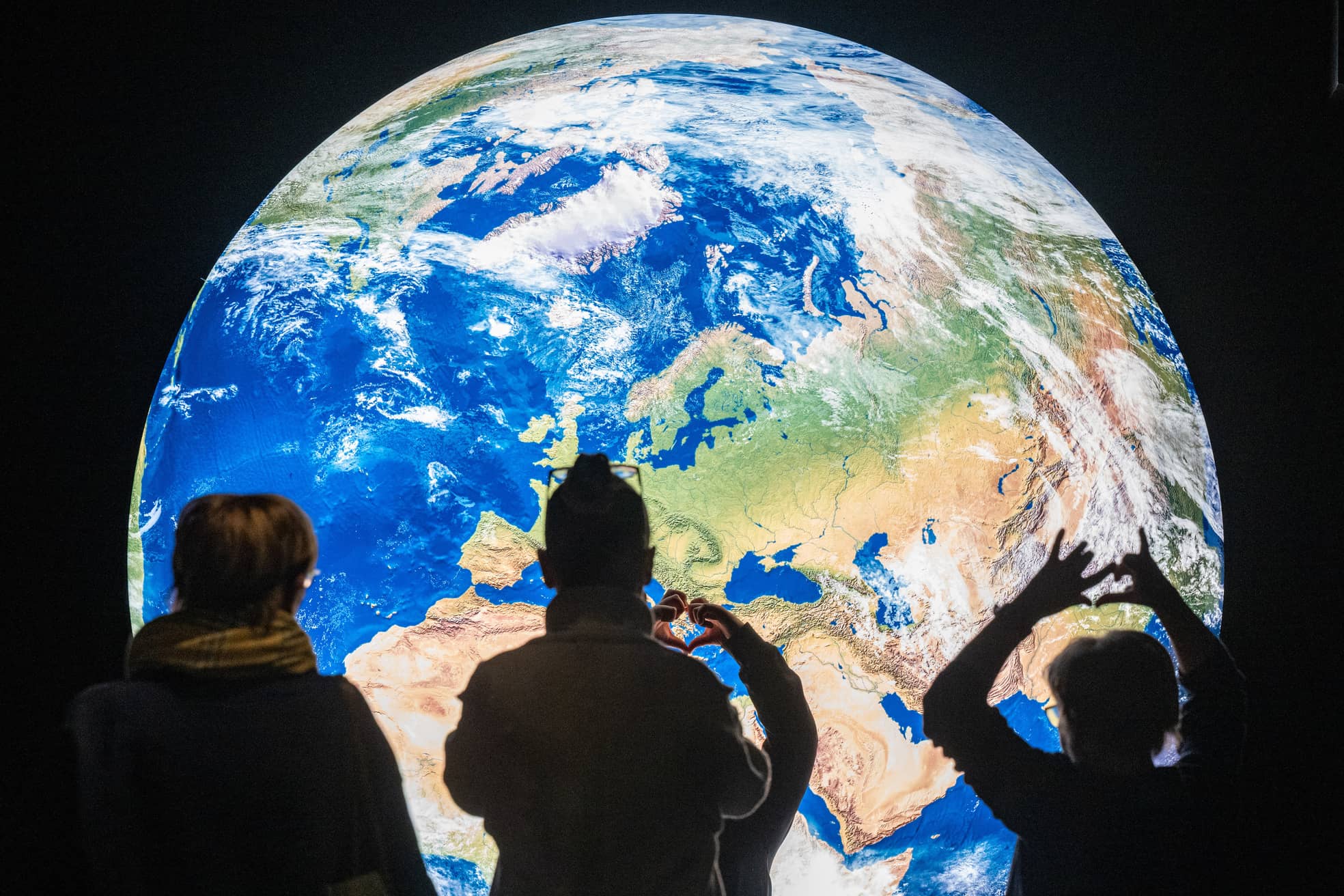 Im Nawareum in Straubing stehen Menschen in der Ausstellung vor einem großen Bild der Erde.