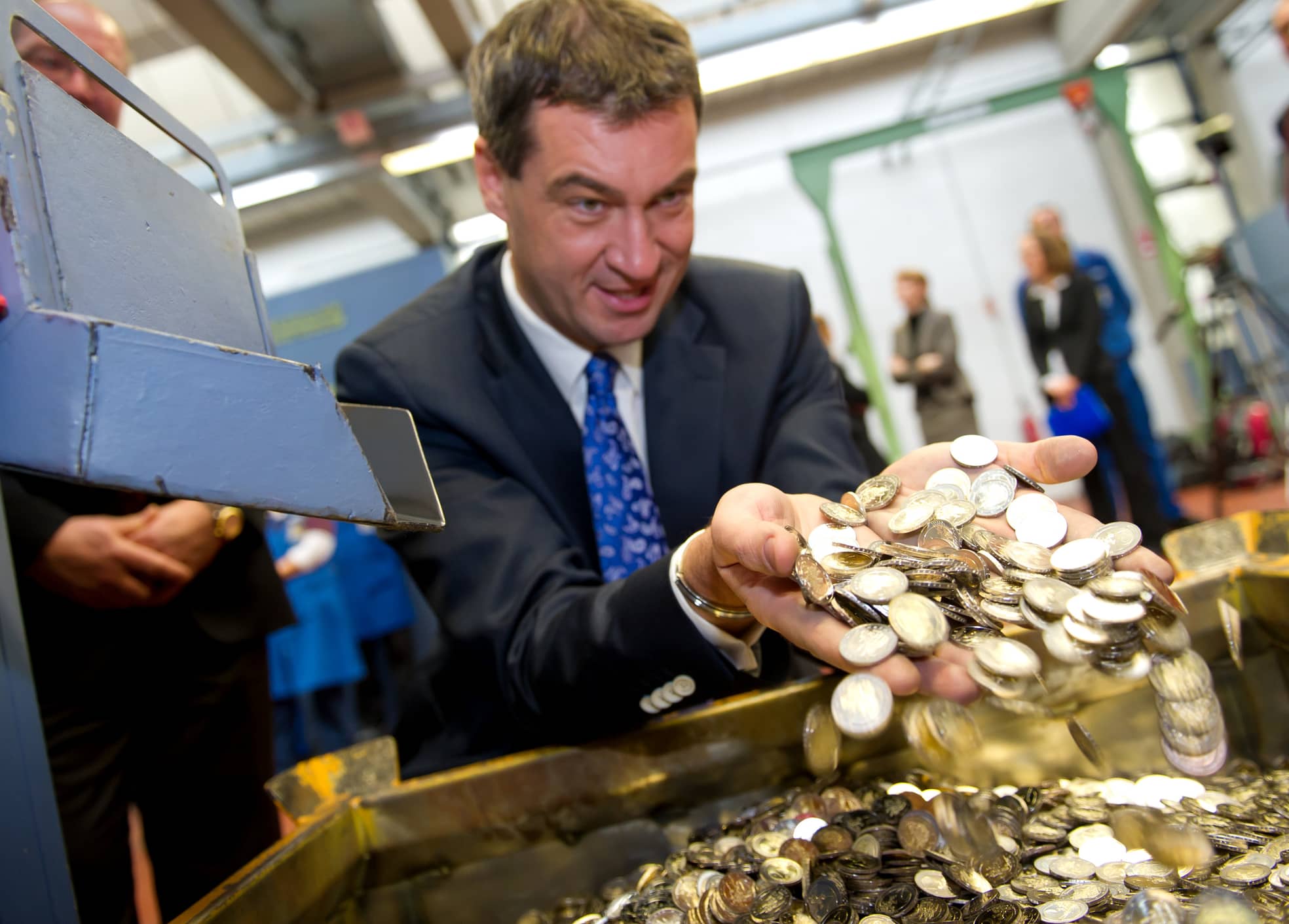 Markus Söder, fokussiert aufs Geld: Diese Zwei-Euromünzen, die er fotofreundlich 2011 rieseln lässt, sind übrigens mit einem der größten Finanzdebakel in der Historie Bayerns bedruckt: Schloss Neuschwanstein.