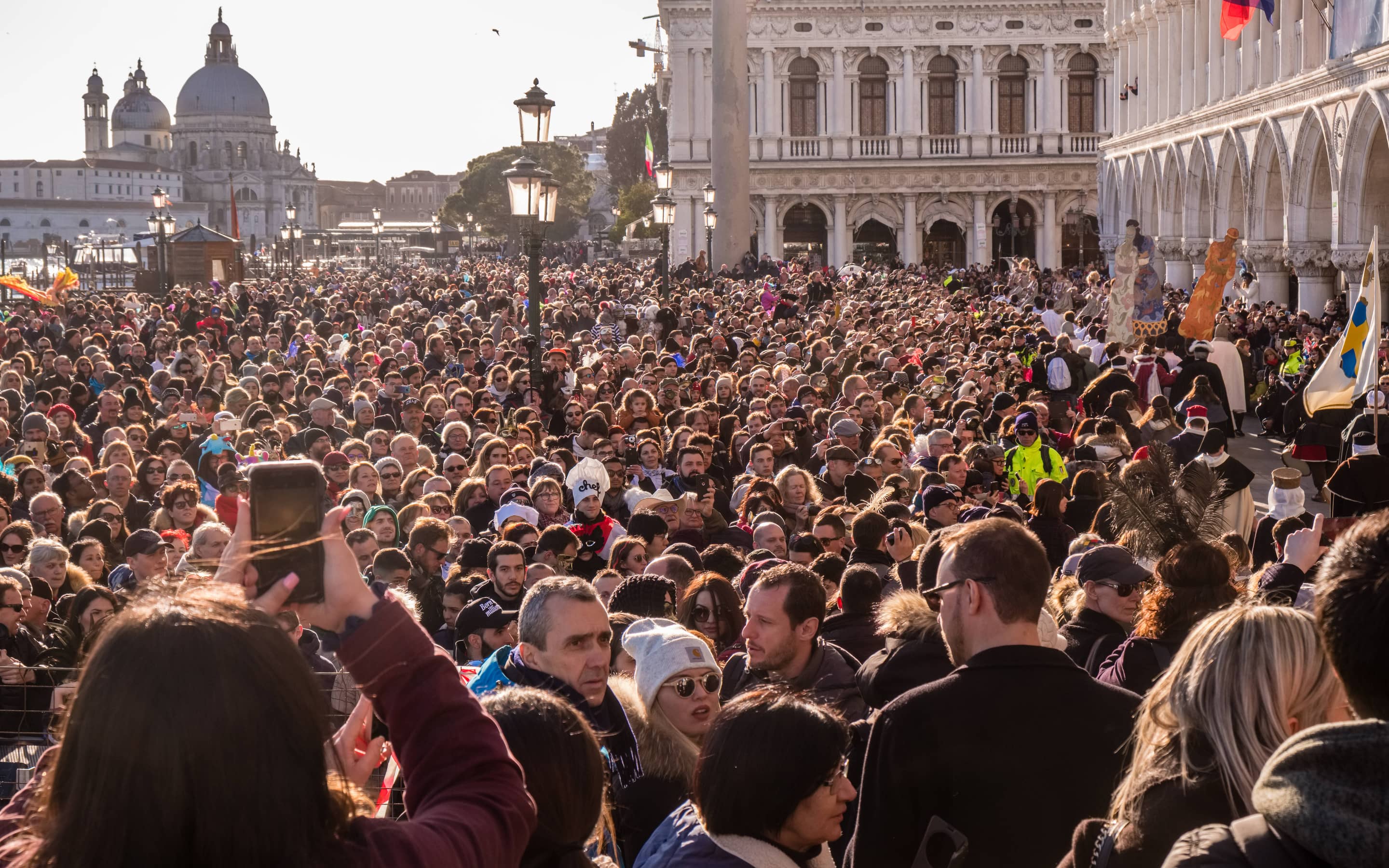 Menschenmengen beim berühmten Karneval, im Hintergrund die Basilica Santa Maria della Salute.