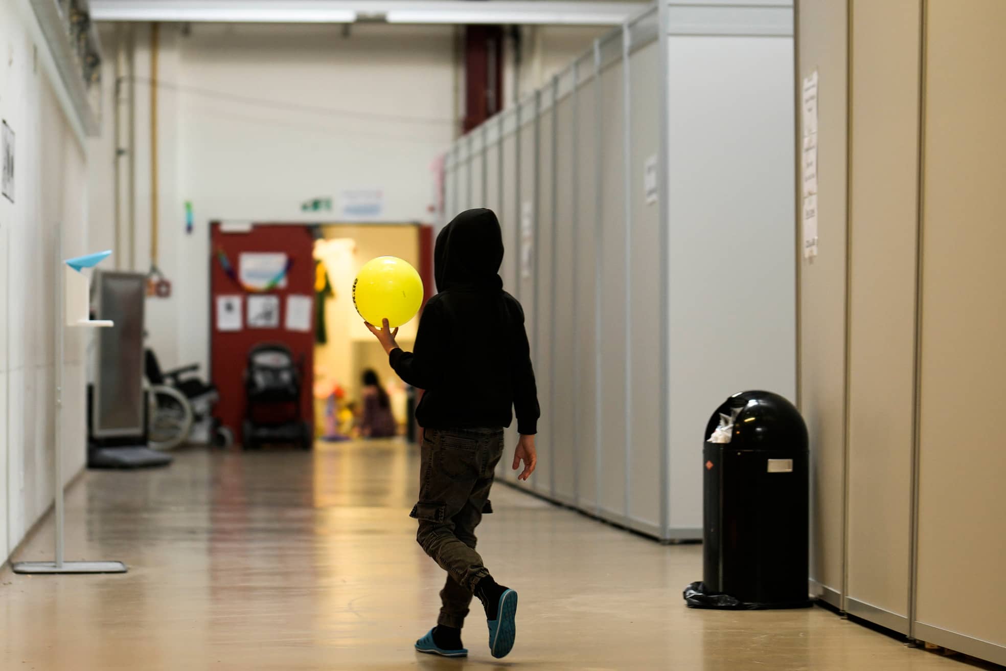 Hinter der Tür warten noch mehr: Ein Junge durchquert den Gang der Flüchtlingsunterkunft im alten Flughafengebäude von Berlin-Tegel.